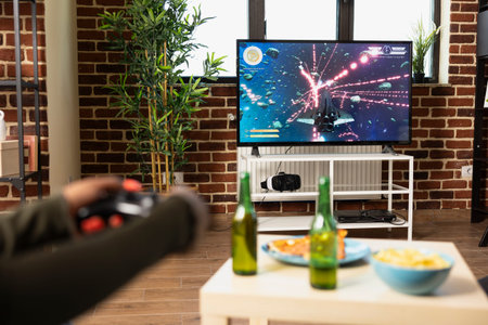 People enjoying gaming indoors with beer and snacks on sunny afternoon at home. Black female player...