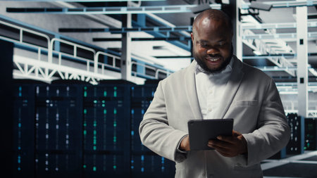 Close up of technician walking in data center, using tablet to check equipment for system stability....