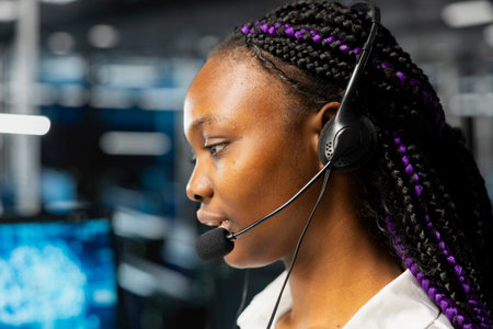 Close up of female engineer in data center speaking in headset mic, using AI to provide user...