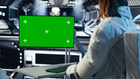 Astronaut reviewing onboard analytics on green screen monitor before stepping outside space station....