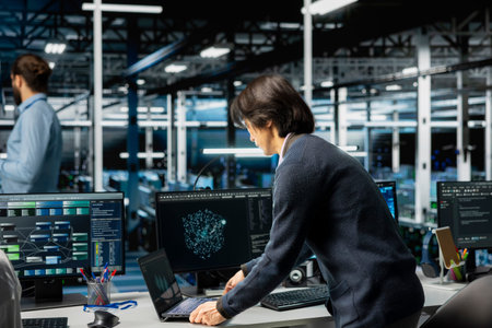 Software developer in server room office using device to review infrastructure diagnostics. Man in...