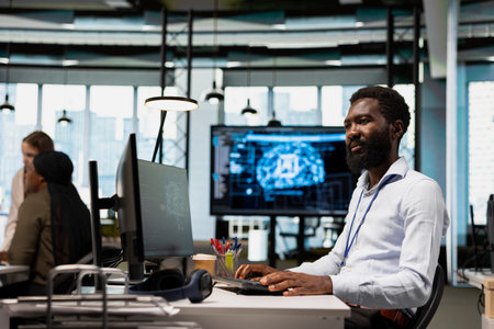 System administrator writing code, developing machine learning APIs. African american man in office...