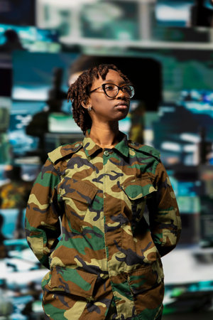 Soldier wearing camo uniform in command center, looking at multimedia display with tactical visuals....