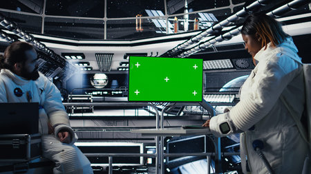 Astronaut reviewing onboard analytics on green screen monitor before stepping outside space station....