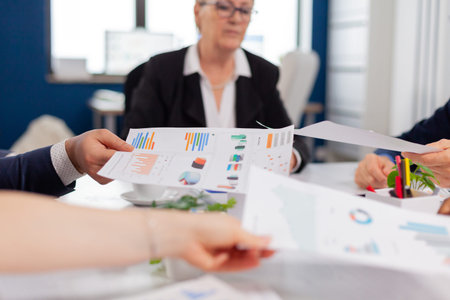 Confident company manager giving working tasks to diverse teamworkers analysing paperwork with...