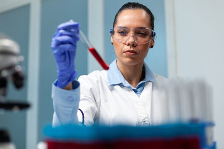 Scientist woman holding blood test tube working at microbiology experiment in medicine biochemistry...