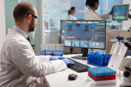 Man scientist working to develop a new vaccine in modern equipped laboratory, typing at computer....