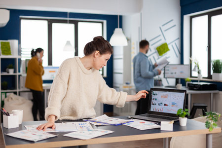 Businesswoman analysing financial statistics standing in start up office. Executive entrepreneur,...