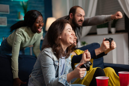 Excited group of multi ethnic friends celebraing victory aftter winning at online video games using...