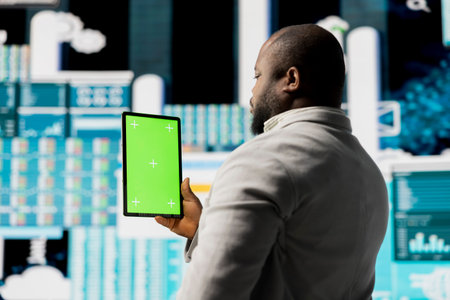 Young african american leader reviewing mockup screen with data insight for business development, surrounded by fintech charts and KPI projections. Financial performance and decision making.の写真素材