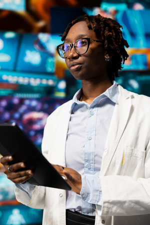 Healthcare researcher using tablet app, looking at medical data, working on disease prevention research. Scientist doing treatment development, looking at patient scans on touchscreen deviceの写真素材