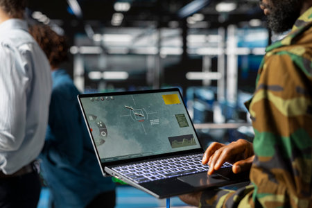 Black army soldier in data center using laptop to overview satellite data via drone control, looking...