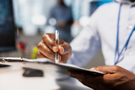 Close up of office worker writing on clipboard while seated at desk, doing accounting tasks....