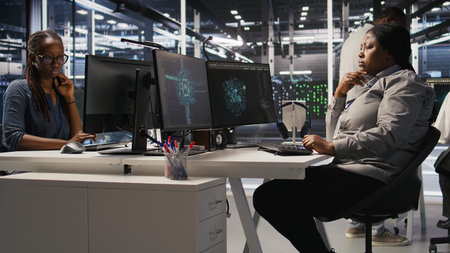 Data center system administrator using PC to monitor neural network AI visualization. African...