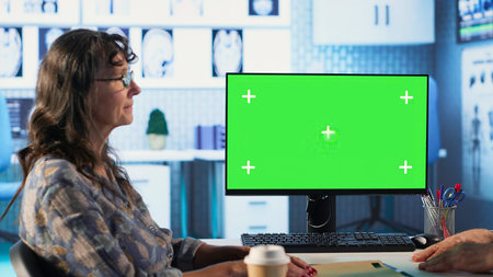 Old general practitioner discusses with female patient next to green screen, offering details from...