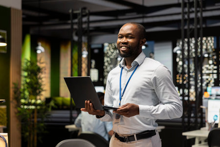 Portrait of cheerful businessman in office managing schedules on laptop, organizing calendar...