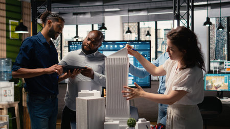 Urban development experts use teamwork to envision a new housing project, studying 3D models for...