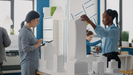 Women using digital tablet to design building model for urban construction in architectural office....
