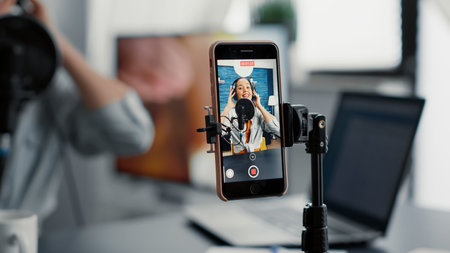 Social media famous influencer recording video blog with modern smartphone while speaking to...