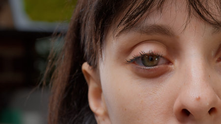 Macro shot of one green eye and half face in front of camera, authentic beautiful woman smiling....