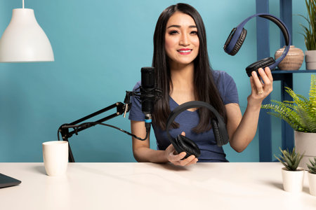 Social media influencer demonstrating and comparing two wireless headset, as she speaks into mic at...