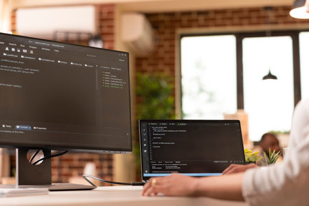 Closeup of female freelancer uses multiple device screens, writing programming scripts at home....