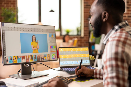 Black male illustrator using stylus and graphic tablet to create digital artwork from home. African...