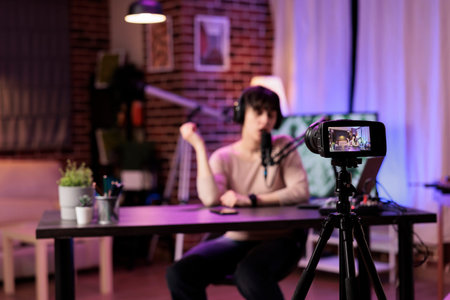 Focus shot on modern camera recording vlogger in blurry background talking about personal...