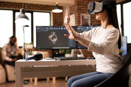 Female engineer wearing VR headset and gesturing hands in 3D simulation to review clamp model. Young...