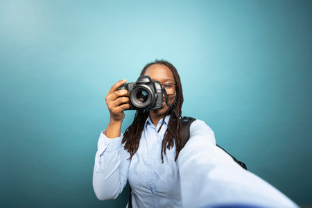 POV of Black female photographer recording herself with a DSLR. African American woman in blue...