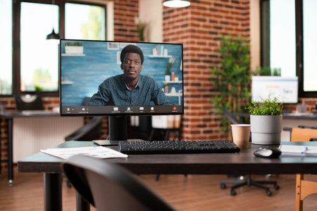 Empty brick wall room equipped with desktop showing black businessman conducting virtual meeting....