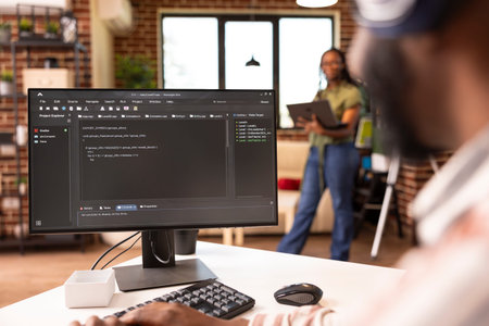African american software developer typing at home desk, refining code and solving bugs on computer. Male remote worker focuses on improving application performance in home workstation.の写真素材