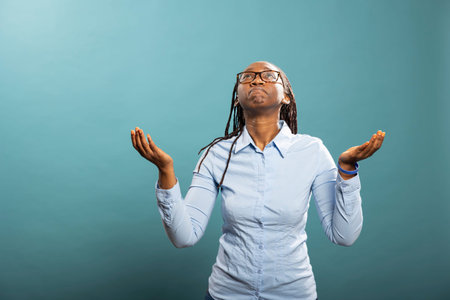 Black female individual with sad expression, looking upwards with hope, silently wishing for...