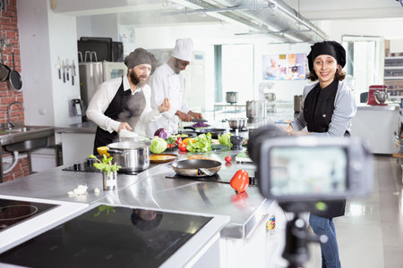 Diverse culinary team recording a cooking class lesson on camera, teaching food prep and plating techniques for an internet audience. Chefs hosting a video tutorial master course.の写真素材