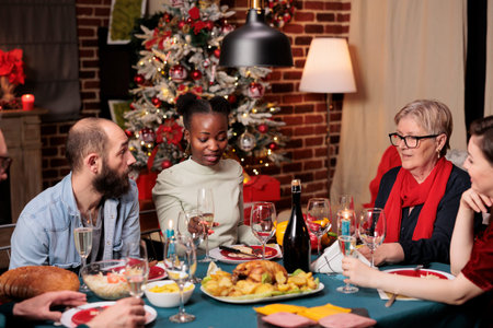 People raising glasses for toast during christmas dinner, enjoying family time at home with...