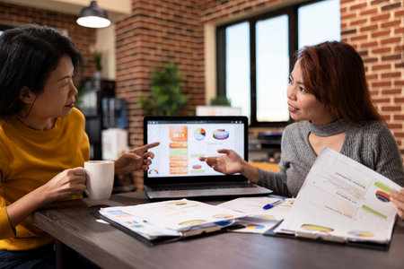 Financial expert advising an investor on market trends, examining the charts on laptop. Business...