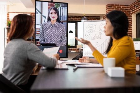 Company advisors seated at desk with documents, shares business updates with a remote client via...