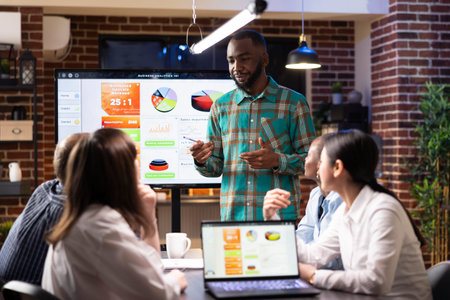 African american manager discussing with coworkers during late night meeting in brick wall...
