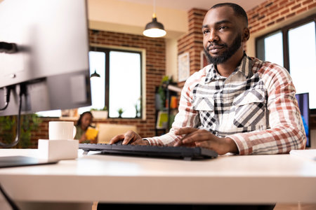Confident man working from home, checking company revenue and reviewing analytics on computer. Male...