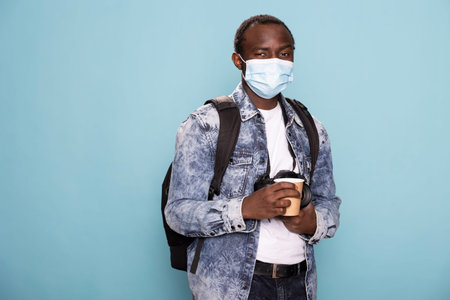 African American man in a denim jacket and protective mask, ready for a photoshoot, gripping his...