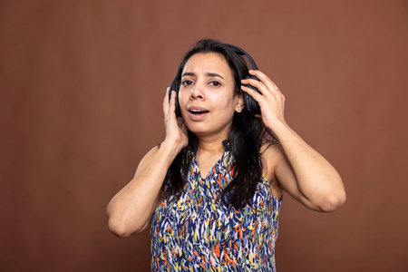 Surprised pretty woman wearing headphones with mouth open and eyes wide, looking at camera. Portrait...