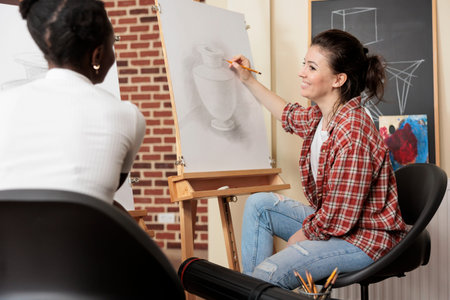 Two diverse girls best friends enjoying creative activities together, having enjoyable experience at...