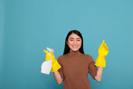 Asian happy glad housewife from daily work holding spray in yellow rubber glove, Cleaning home concept, Cheerful satisfied woman with positive mindset from day to day choresの写真素材