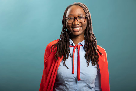 Cheerful african american woman confidently poses in blue background studio, wearing a blue shirt...
