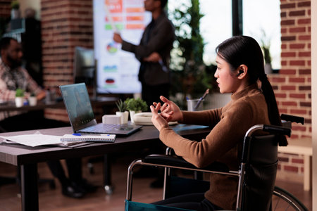 Worker with chronic impairment using remote teleconference chat on laptop, sitting in wheelchair. Female employee with disability meeting on online videoconference call, telework.の写真素材