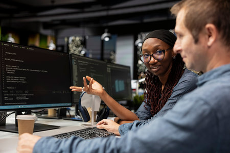 Smiling engineer and coworker cooperating in AI focused startup, designing, coding and debugging applications. Cheerful IT experts doing brainstorming, testing code, doing quality assuranceの写真素材