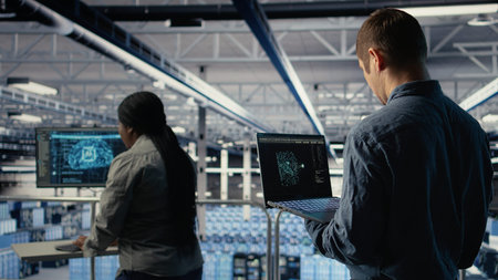 Software developer in data center checks AI dashboard using laptop during routine systems review....