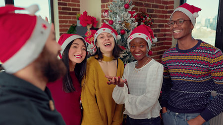 Multiethnic group of employee recording video in festive office, filming on camera during christmas...