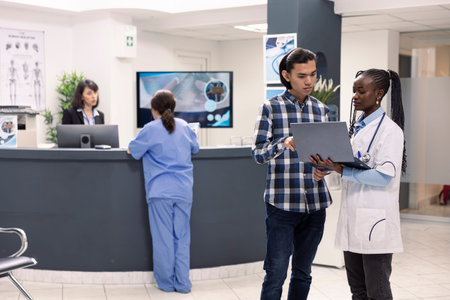 Young asian man discussing diagnosis and treatment with female physician in hospital waiting area....