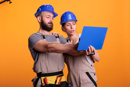 Team of renovators analyzing papers on clipboard, taking notes of construction measurements....